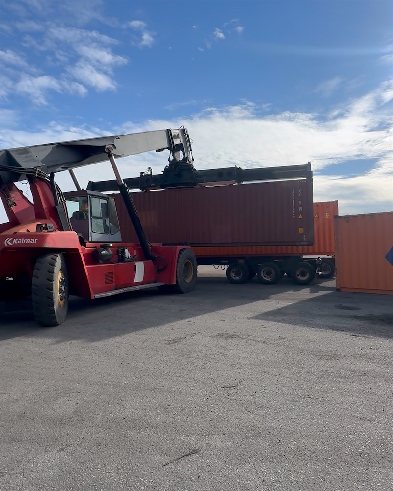 Reach stacker lifting a shipping container onto a trailer