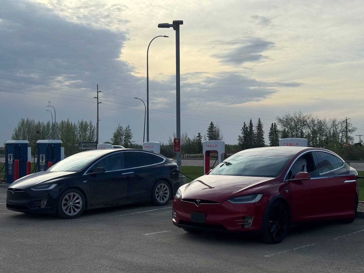 Black and red Tesla Model X charging at a Supercharger station