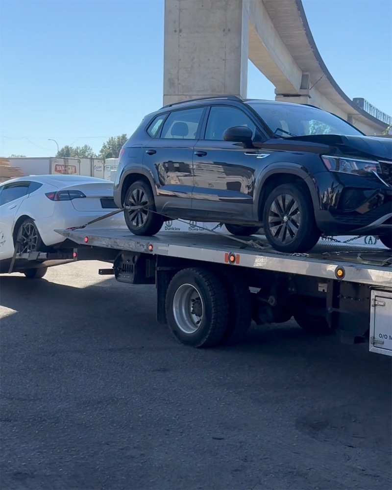 Flatbed tow truck delivering two vehicles to the export yard